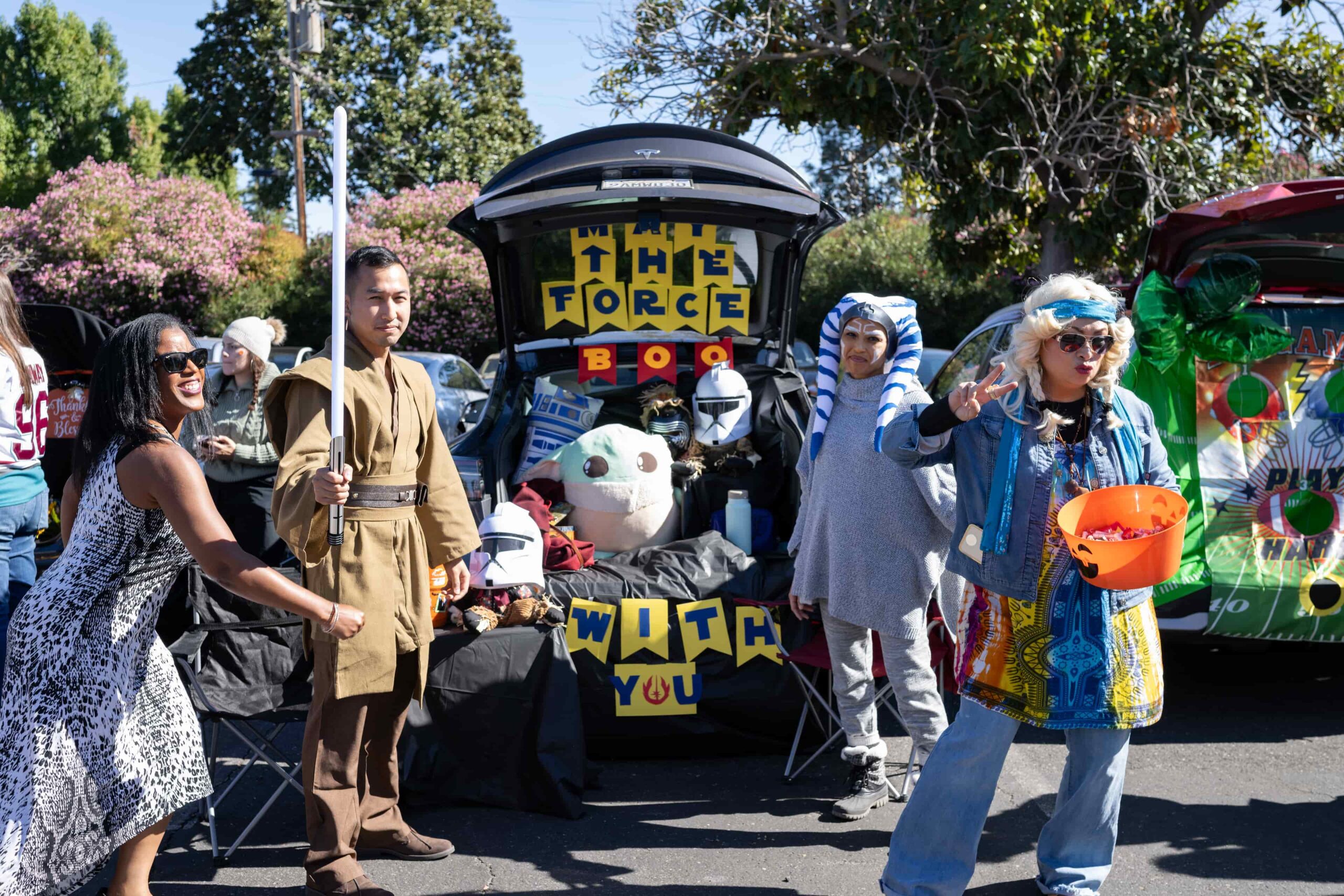 Smiling kids of all abilities in costumes receiving candy at an inclusive Trunk or Treat event.